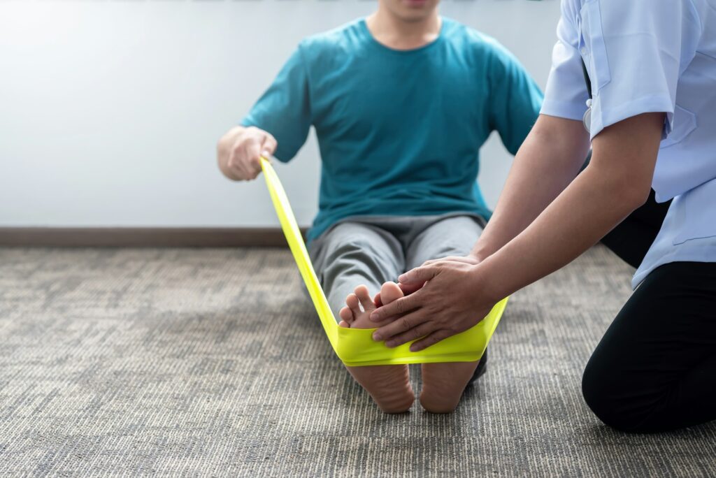 Physical therapist assisting a patient with a foot exercise using a resistance band.