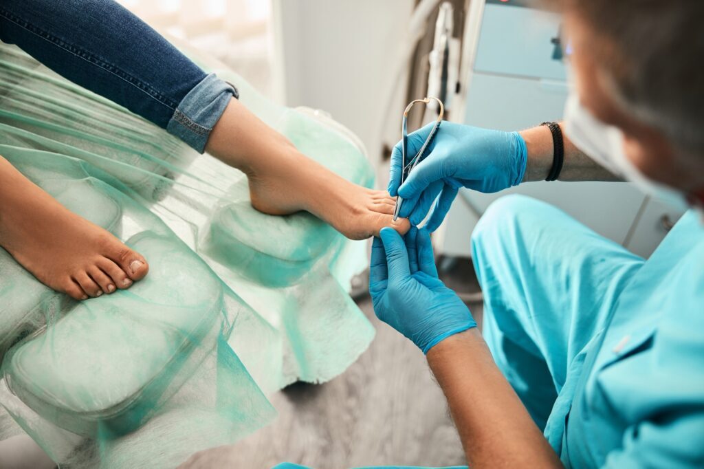 Healthcare professional examining a patient's toe with a medical instrument.